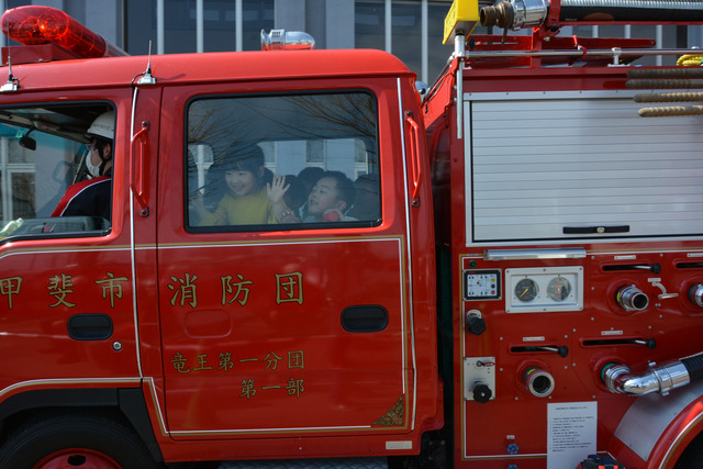 甲斐市消防団フェスタで女の子と男の子二人が消防車試乗体験している写真